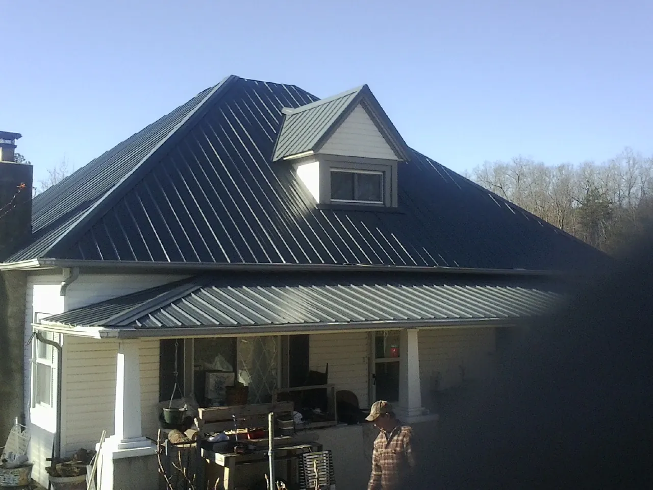 Dark blue standing seam metal roof with a dormer above a front porch in Pomeroy